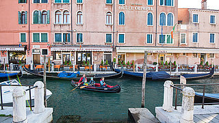 Frau mit 3 Kindern paddelt mit dem aufblasbaren Kanu Adventure in Venedig vor dem Hotel Olimpia